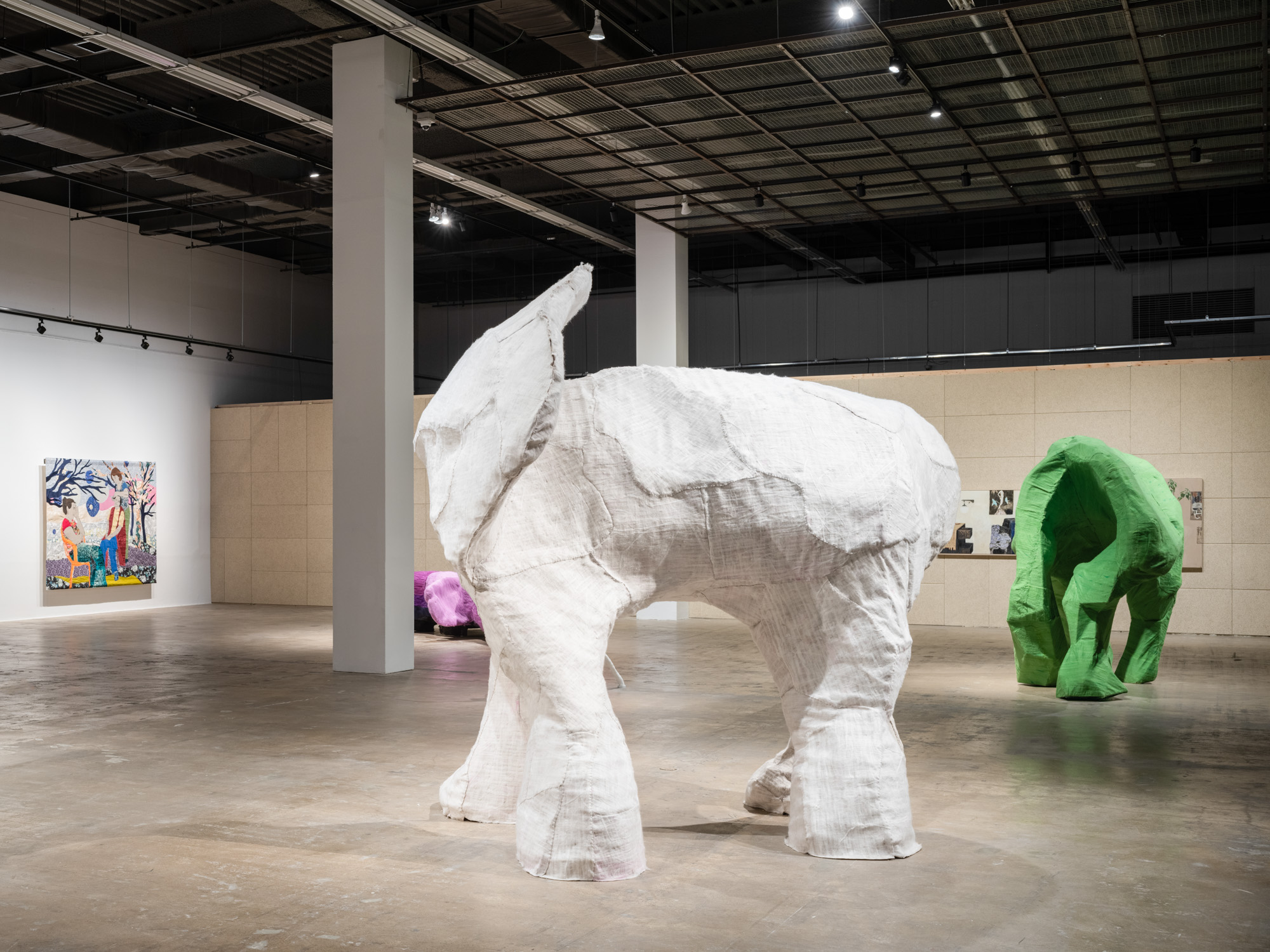 An exhibition space features one white elephant-like sculpture in the middle with two similar sculptures in the back.